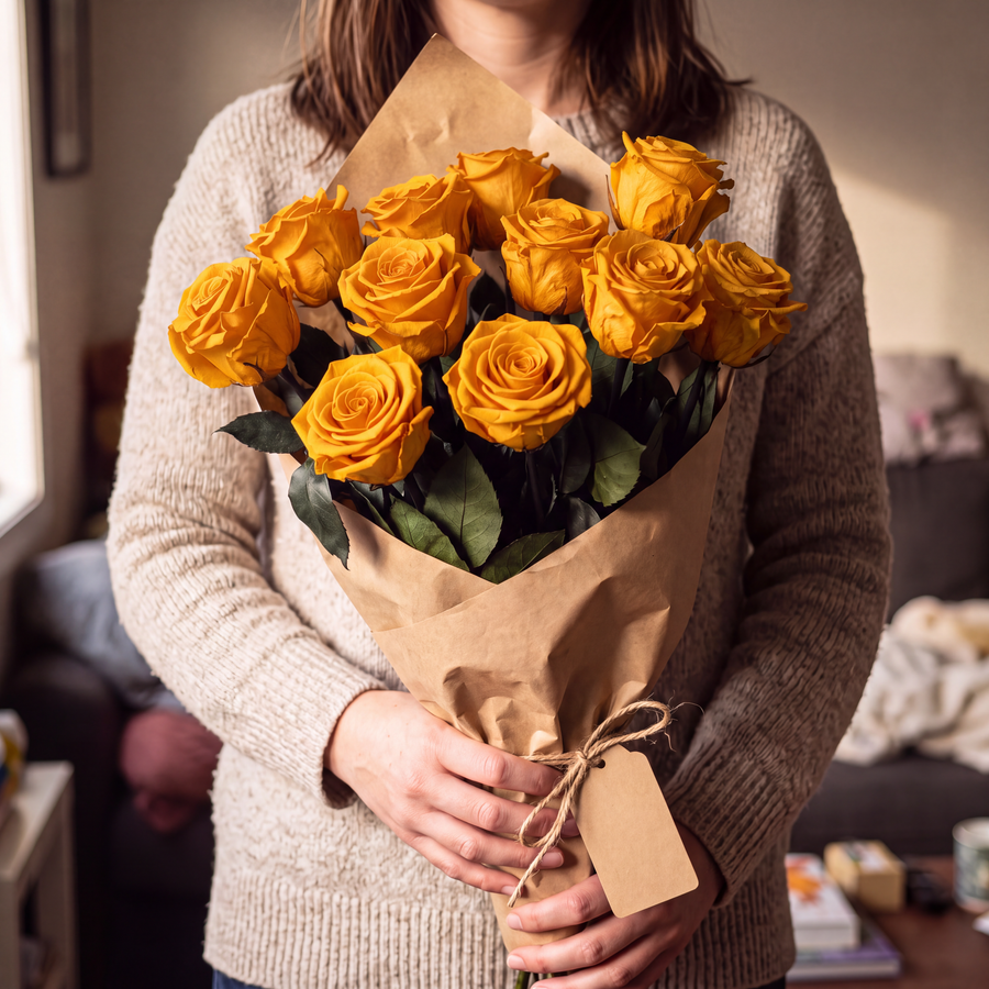 Woman holding a kraft-wrapped bouquet of yellow long stem preserved roses